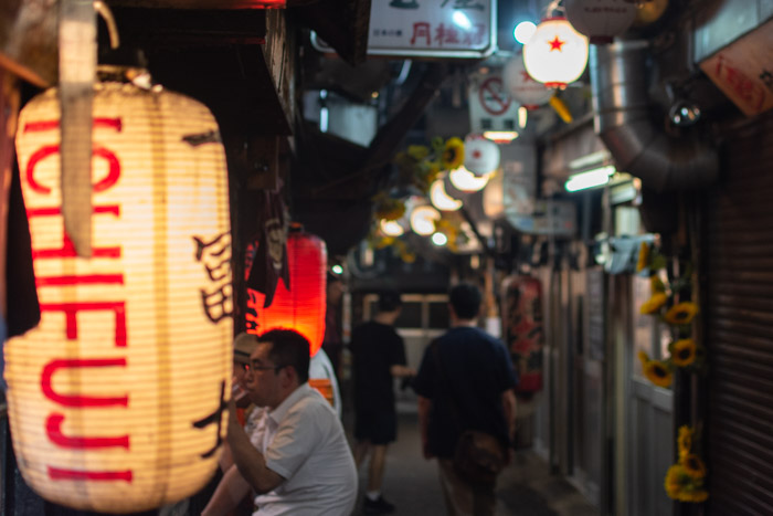 Diners eating in Omoide Yokocho (Piss Alley) at night.